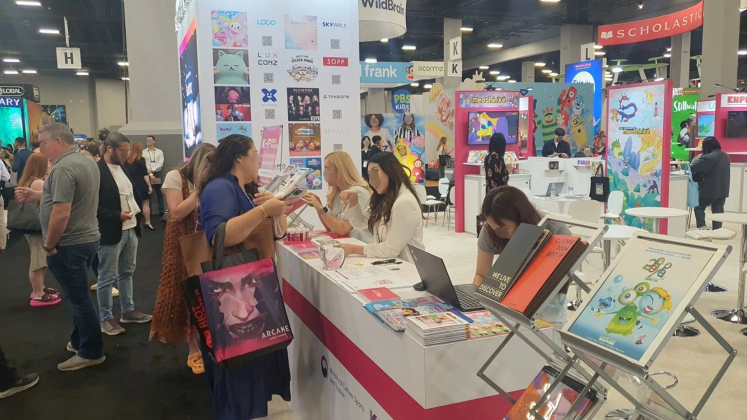 Visitors at the Korean Pavilion counter with K-IP character graphics and brochure racks on the Licensing Expo 2024 show floor