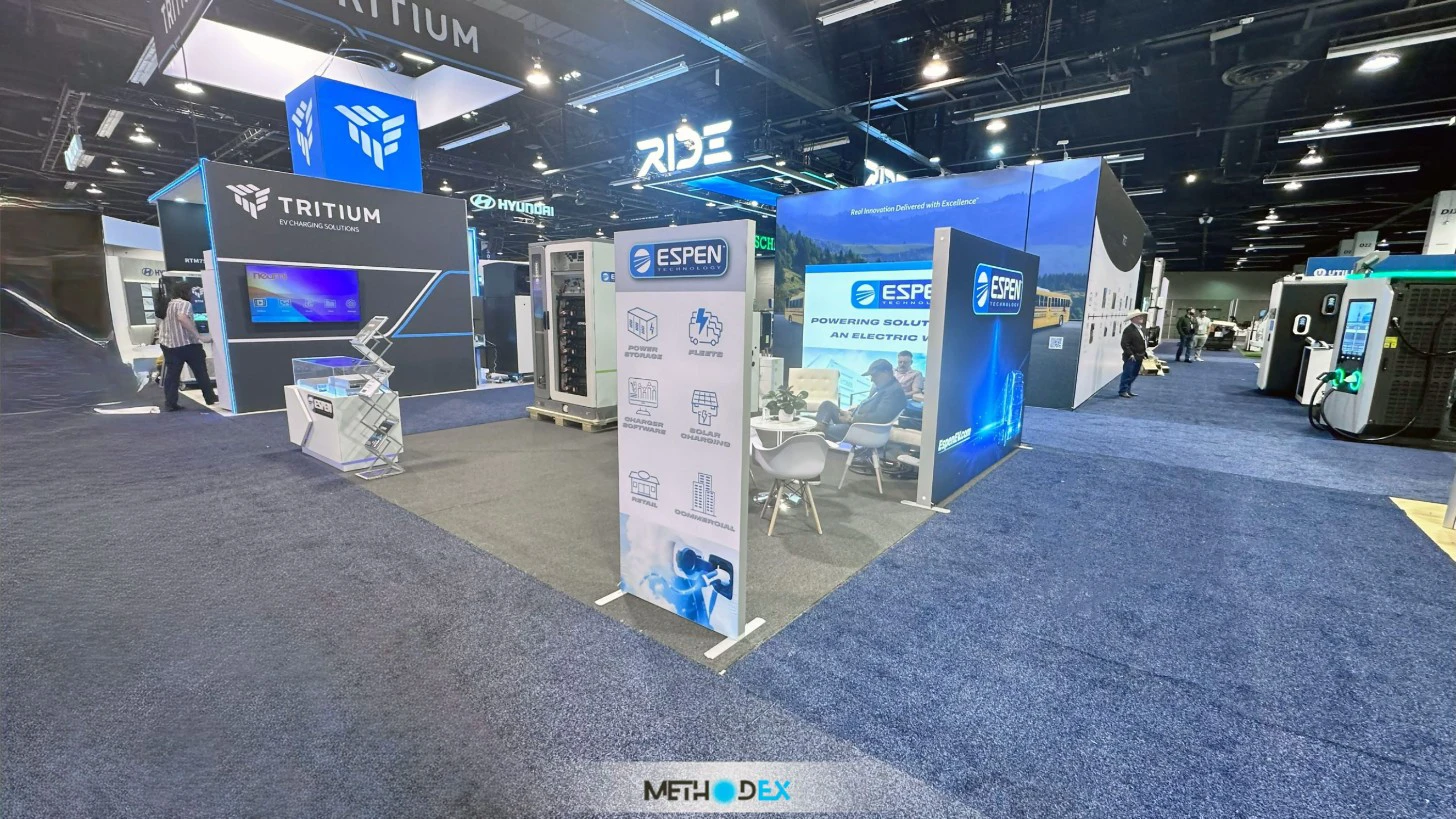 Espen Technology booth built by Methodex with blue backlit walls, a white graphic tower, and white chairs on a gray carpet
