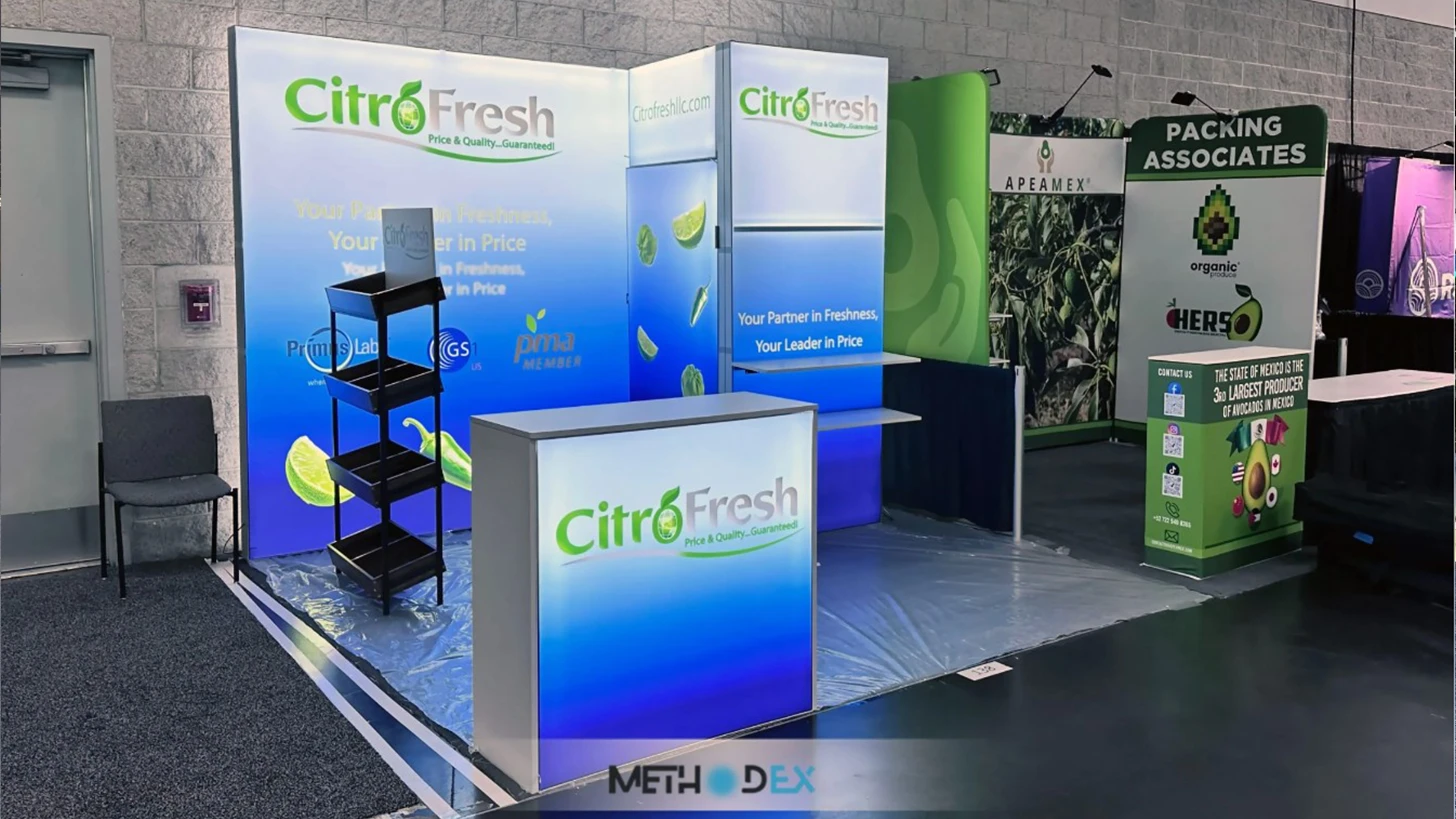 Backlit blue and white Citro Fresh booth with a lit counter, a black tiered display stand, and lime and pepper graphics on the back wall
